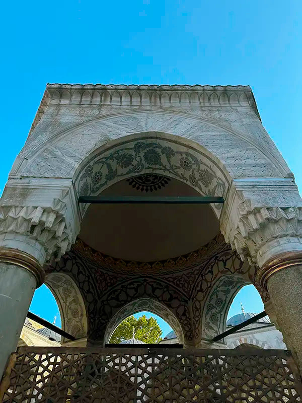 View of the historical fountain from below, painted and carved ornamentals are seen