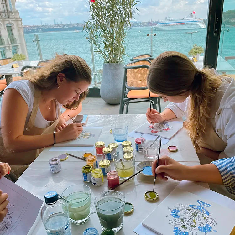 Young women painting a floral design on square tiles with Golden Horn view venue