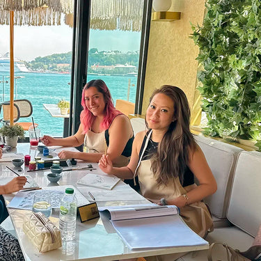 Young women painting with brush n square ceramic tiles